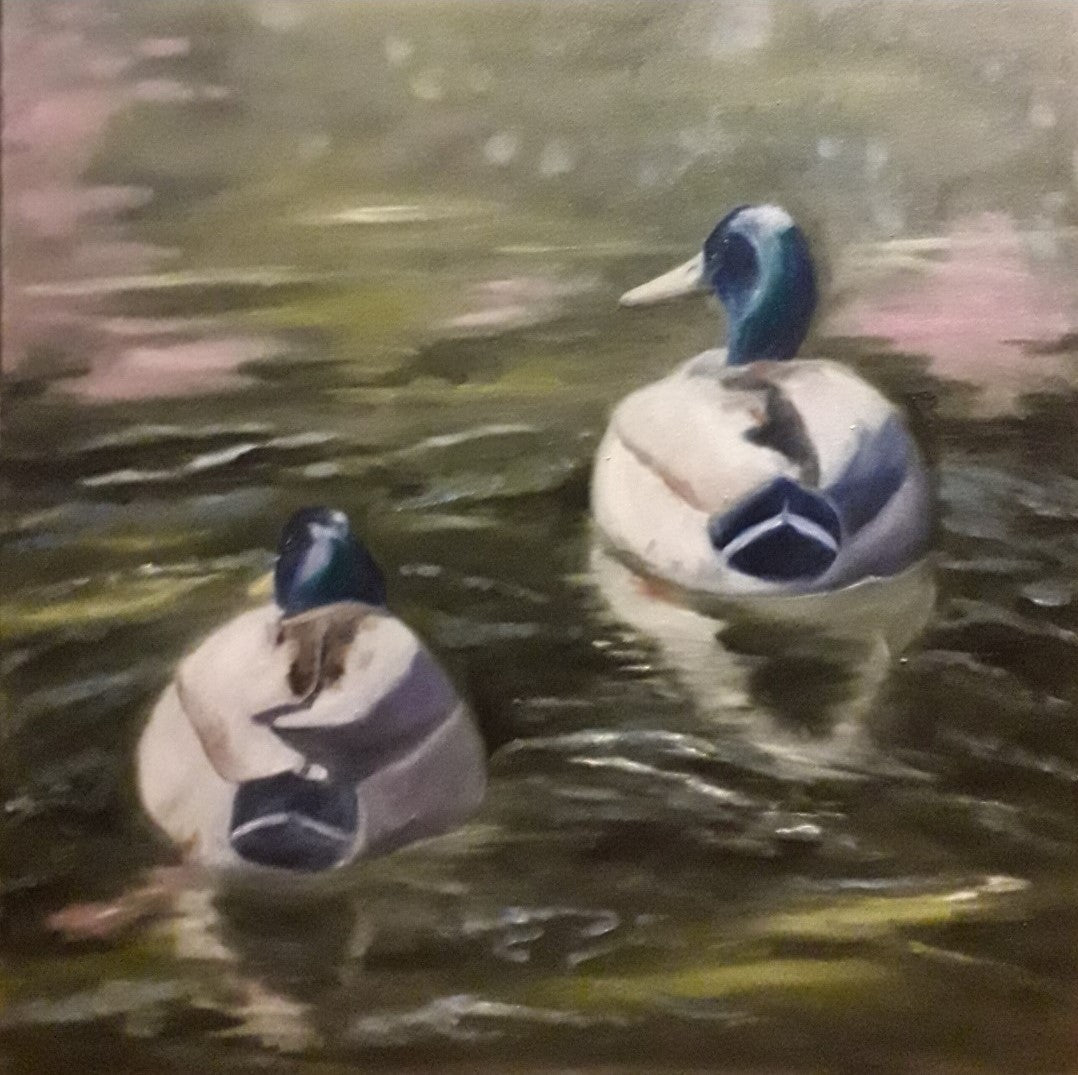 Zwei Stockenten schwimmen auf einem Teich, ihre Rücken dem Betrachter zugewandt. Die Enten sind in Weiß- und Blautönen gehalten und spiegeln sich im leicht trüben Wasser. Der Hintergrund zeigt verschwommenes Grün und Braun, was auf Bäume und Uferbewuchs hindeutet. Ölgemälde von Anke Dinkelbach, Künstlerin bei ARTSPACER.