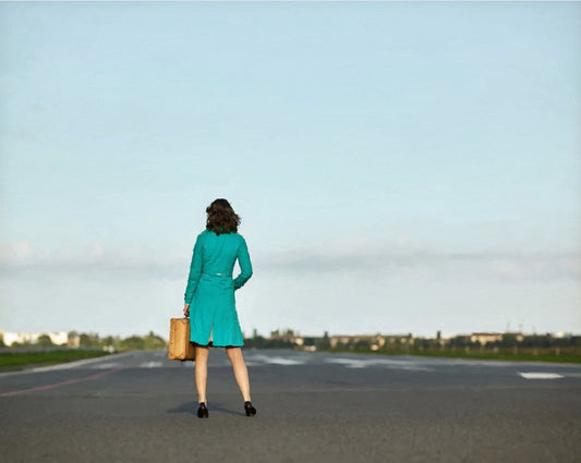 Das Kunstwerk "War's das?" des Künstlers nostrokesbitte ist ein digitales Gemälde im Stil des Fotorealismus. Es zeigt eine Frau von hinten, die in der Mitte eines breiten, asphaltierten Weges steht und einen kleinen Koffer hält. Sie trägt einen türkisfarbenen Mantel und blickt auf einen weiten, klaren Himmel. Die gesamte Szene ist in den sanften, gedeckten Farbtönen einer Morgenstimmung gehalten. Das Gemälde wurde auf Leinwand gedruckt und ist in limitierter Auflage in der Online-Galerie ARTSPACER erhält