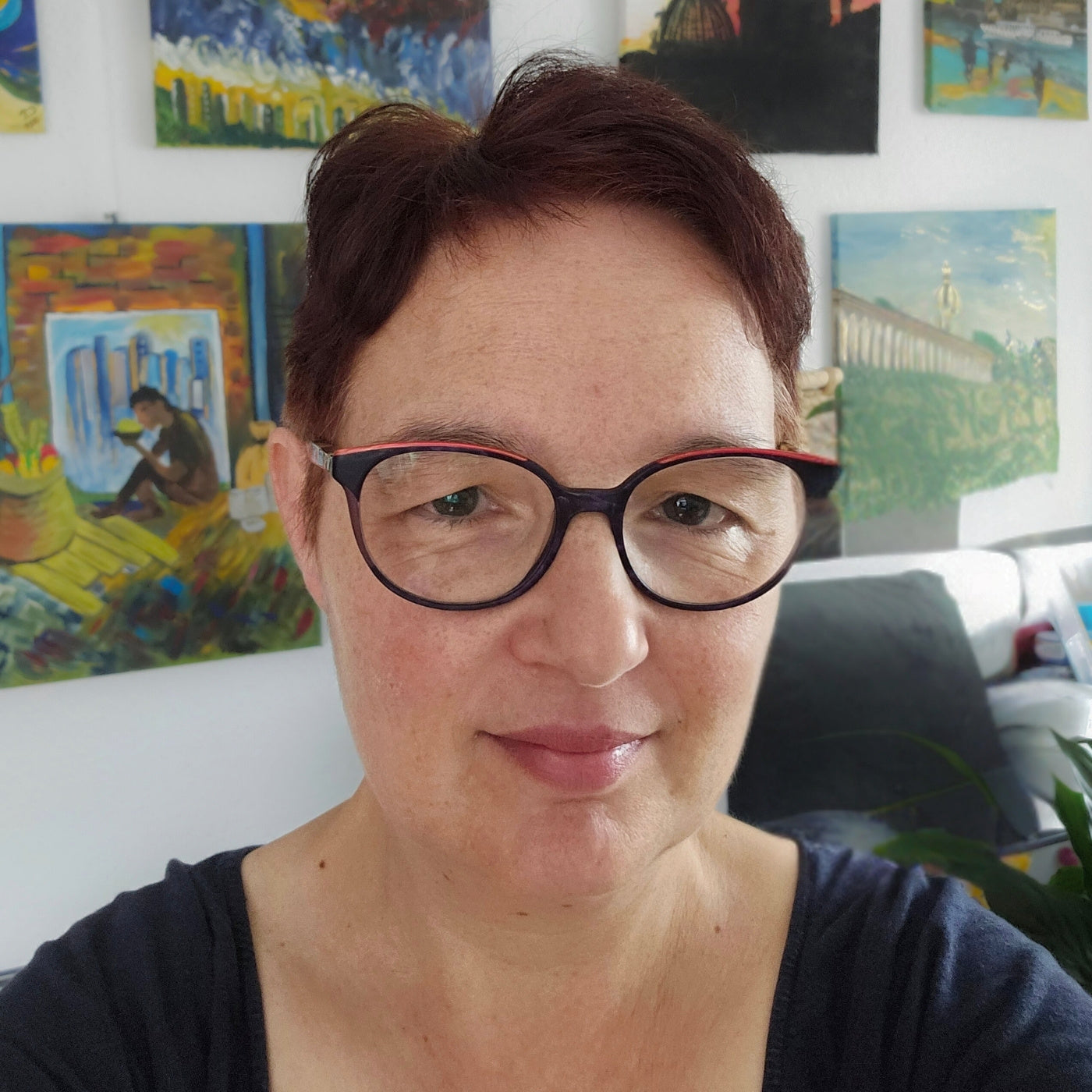 Porträtfoto der Künstlerin Carina Teufel. Eine Frau mit kurzen, dunkelbraunen Haaren blickt in die Kamera und lächelt freundlich.