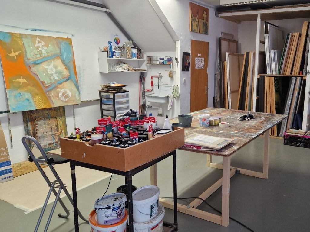 Arbeitsplatz des Künstlers Peter Jaschinski: Eine Auswahl an Acrylfarben und Pigmenten neben einem farbbeklecksten Werktisch im Wuppertaler Atelier.