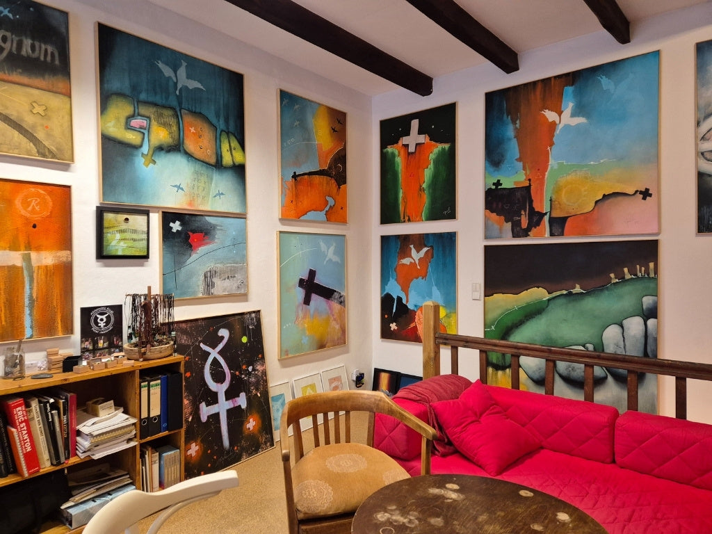 Peters Jaschinskis Arbeitsraum in Wuppertal: Eine Wand voller großformatiger, symbolträchtiger Gemälde über einem roten Sofa – Inspiration und Präsentation im Atelier.