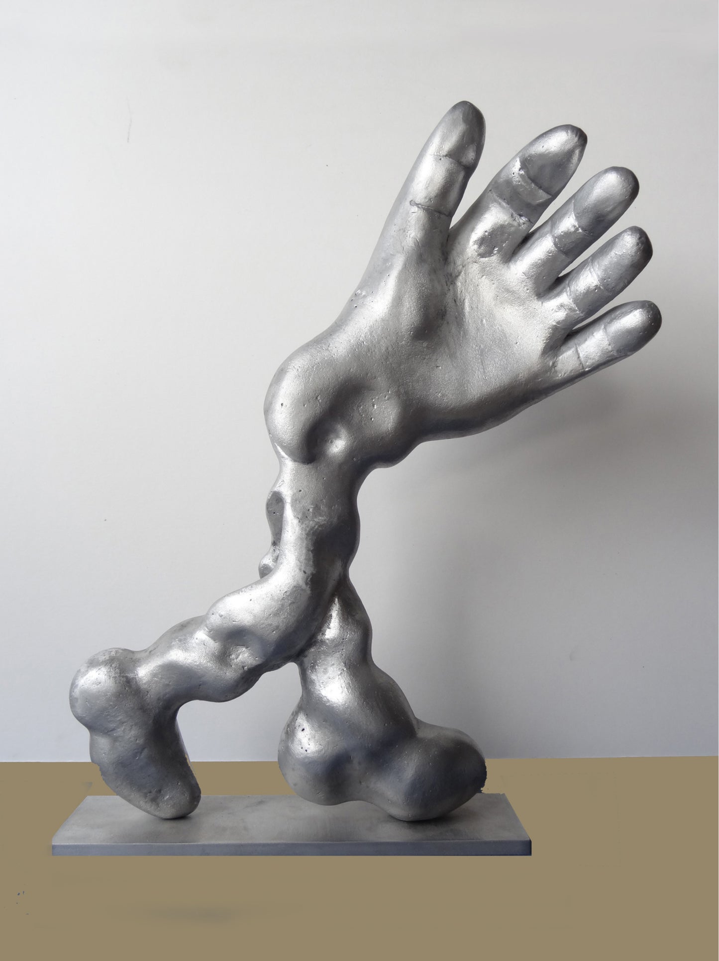 Aluminiumskulptur 'Salute' von Amos Plaut. Abstrakte Darstellung einer Hand und eines Arms, ruhend auf einer rechteckigen Basis. Höhe 41 cm.