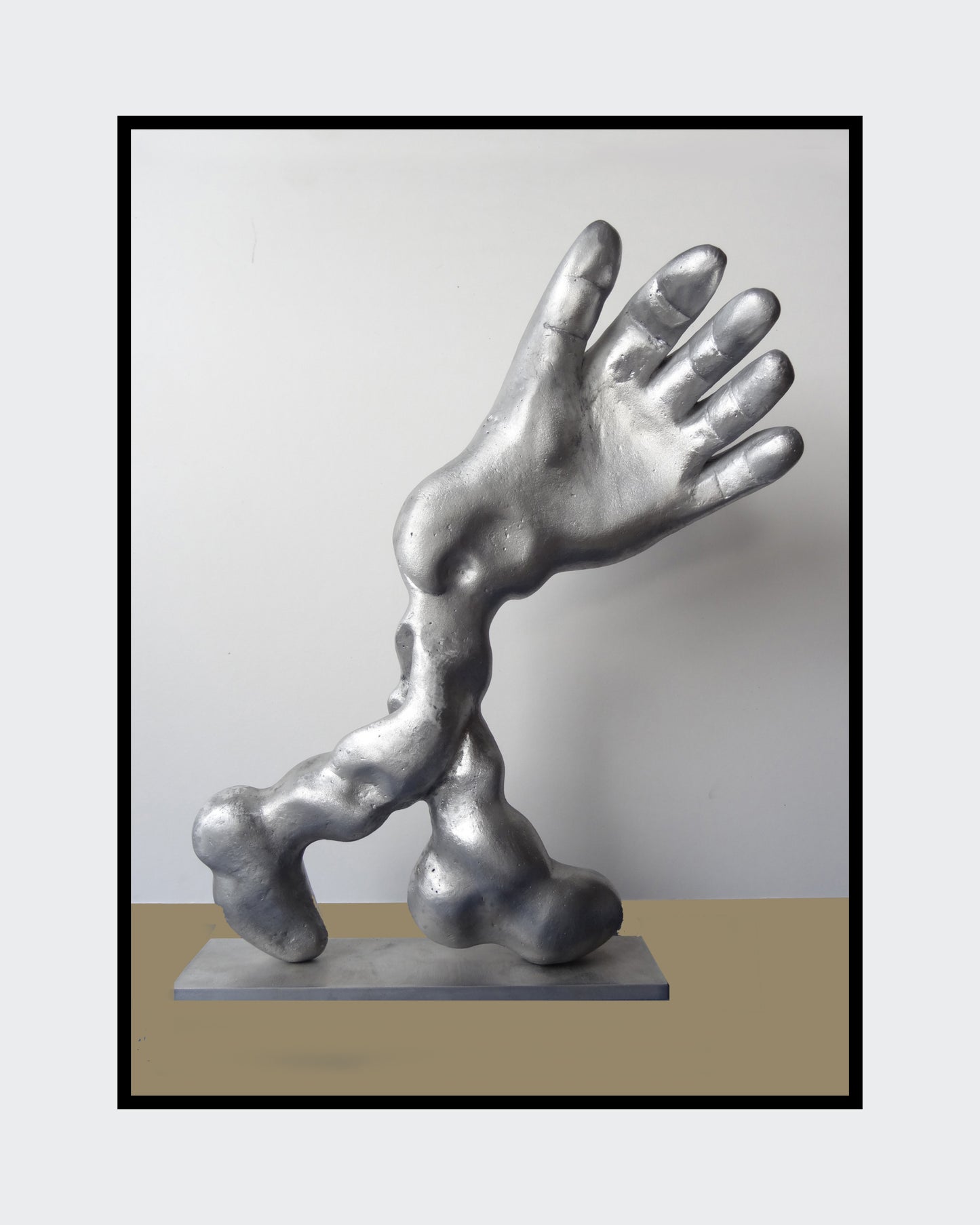 Aluminiumskulptur 'Salute' von Amos Plaut. Abstrakte Darstellung einer Hand und eines Arms, ruhend auf einer rechteckigen Basis. Höhe 41 cm.