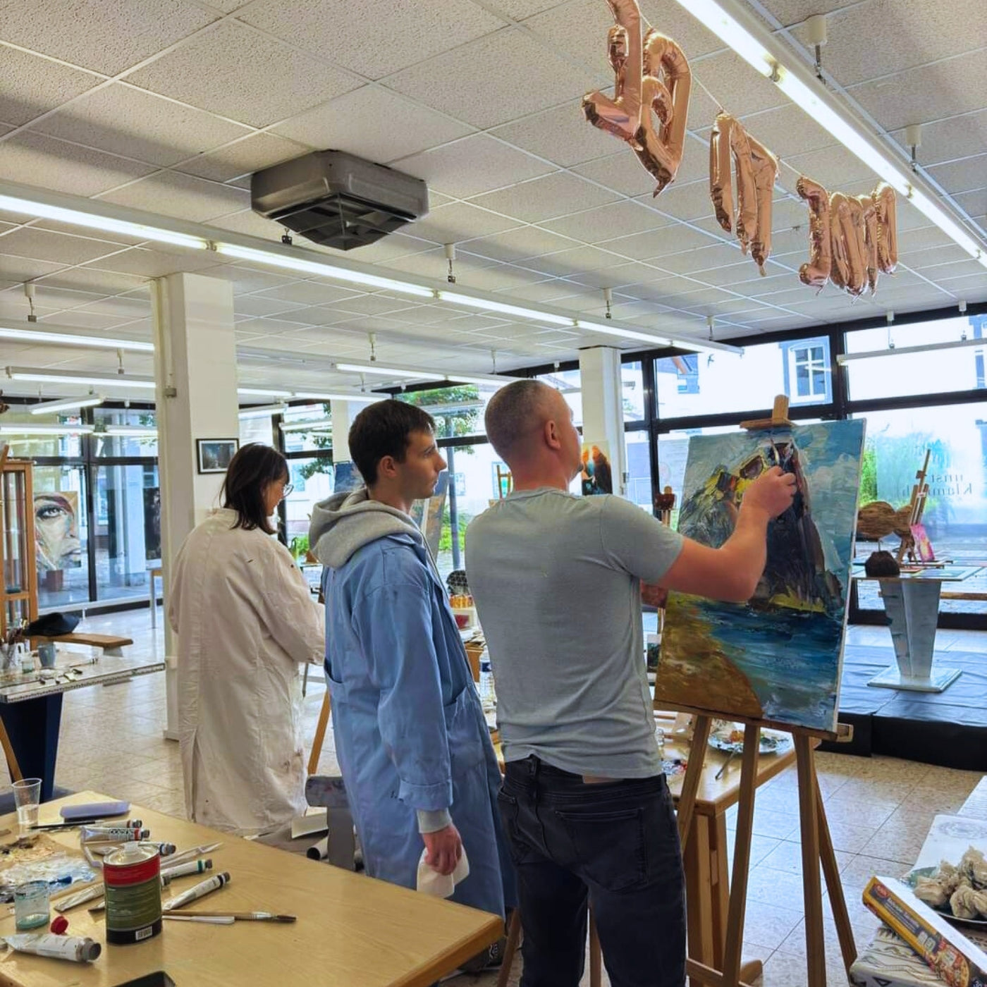 Kunstworkshop von Vadim Lazarev. Der Künstler und 2 weitere Personen sind von hinten zu sehen.