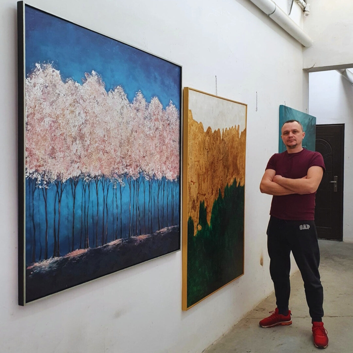 Künstler Vadim Lazarev neben Bilder von ihm, die an der Wand hängen.