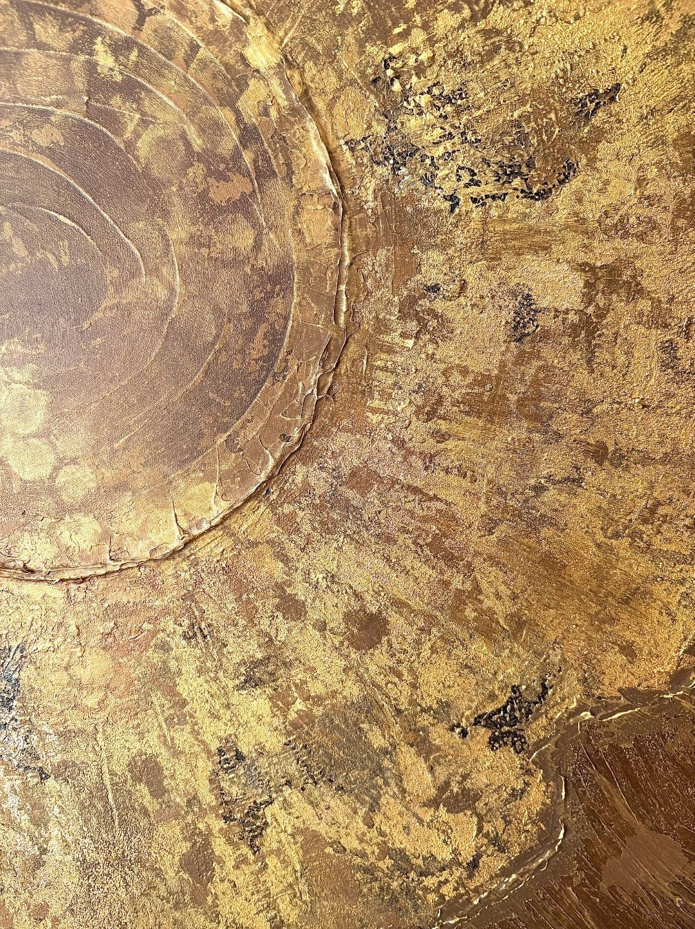 Abstraktes Mixed-Media-Gemälde im Hochformat in Gold-, Braun- und Beigetönen mit stark strukturierter Oberfläche, halbkreisförmiger organischer Form links, konzentrischen Ringstrukturen und strahlenartig verlaufenden Linien über den Hintergrund.