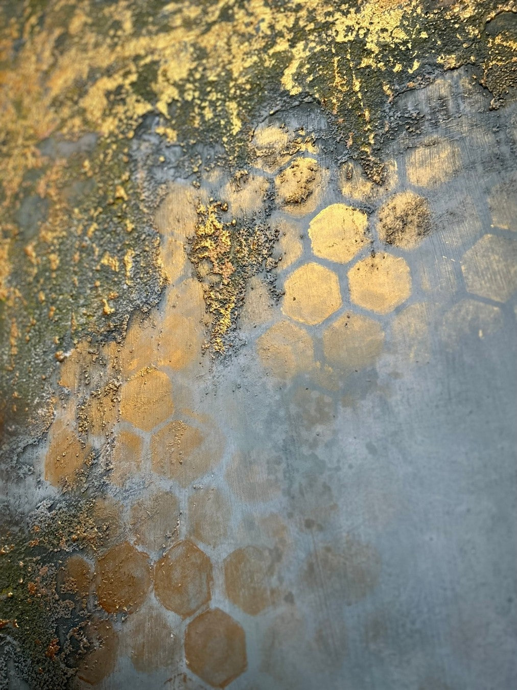 Detailaufnahme eines abstrakten Mixed-Media-Gemäldes in kühlen Grau-, Blaugrün-, Gold- und Beigetönen mit reliefartiger Oberfläche, goldenen Wabenformen und rauen strukturierten Partien.