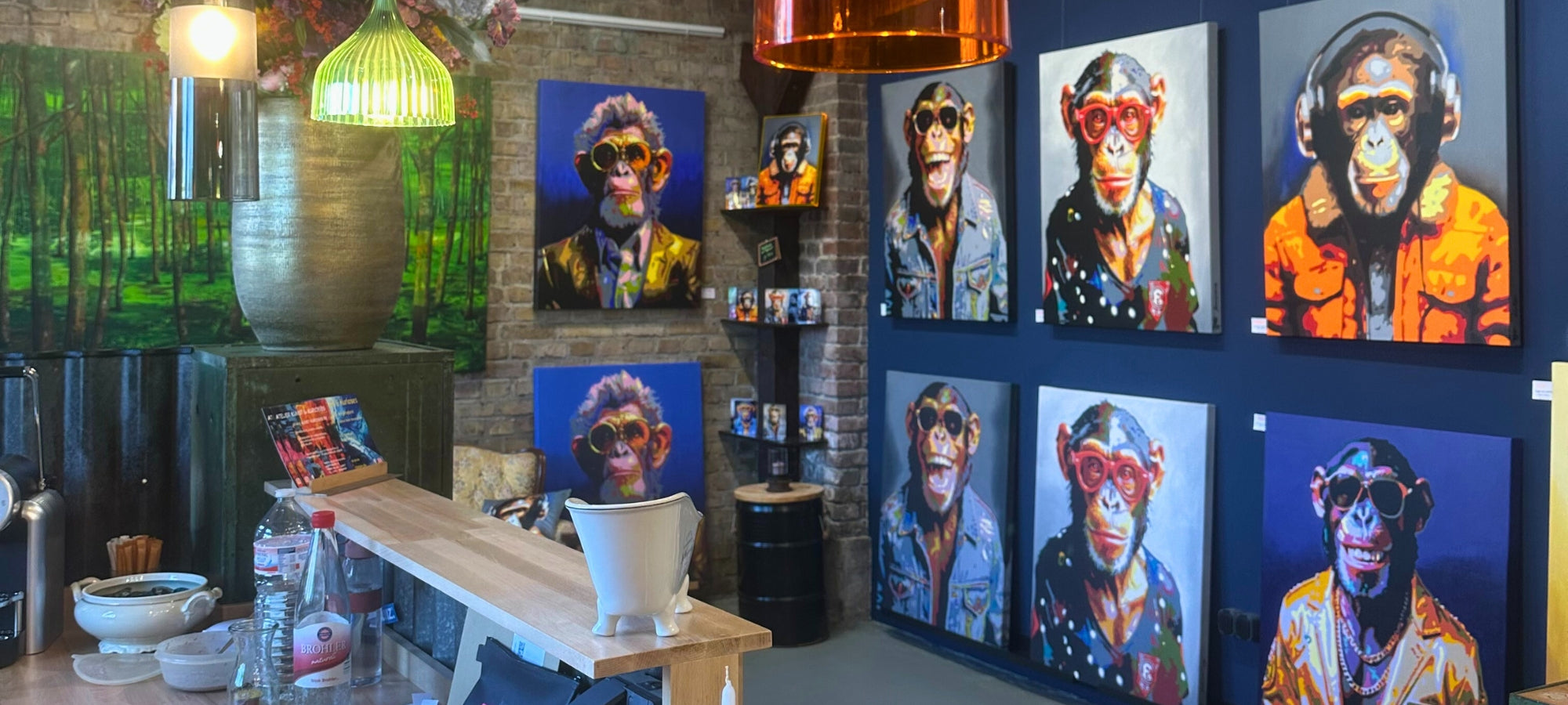 Eine Ausstellungswand mit mehreren Pop-Art-Porträts von Sabine Hoch-Himmighofen, die Affen mit menschlichen Attributen darstellen. Die Gemälde sind in leuchtenden Farben auf einem dunkelblauen Hintergrund gehalten und zeigen Schimpansen mit Sonnenbrillen, Kopfhörern, Anzügen und Jeansjacken, die einen humorvollen und extravaganten Stil vermitteln. Bunter Hund, Areal Böhler