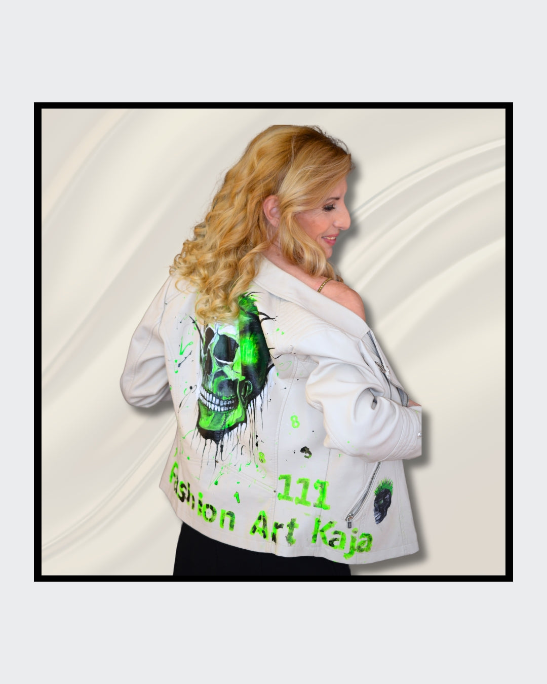 Fashionart von Kaja Schäfer: Eine Person trägt eine handbemalte weiße Bikerjacke mit grünem Totenkopf-Motiv. Das Gesicht ist verdeckt. Dieses Kunstwerk vereint mutige Farben und einzigartigen Stil.