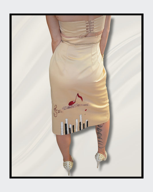Handbemalte Unikate von Kaja Schäfer: Ein einzigartiges Fashionart-Werk, inspiriert von Adeles “Rolling in the Deep”. Der Rock und das Oberteil aus edlem Satin sind mit handgemalten Klavier- und Notenmotiven verziert. Ein Unikat, das Kunst und Mode vereint. 