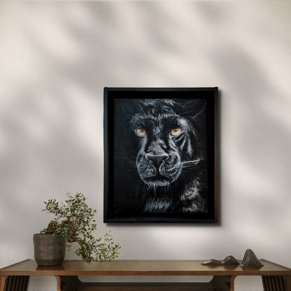 Acrylgemälde einer schwarzen Pantherin in Frontalansicht mit leuchtend gelben Augen vor tiefdunklem Hintergrund, gerahmt in einem schwarzen Schattenfugenrahmen.