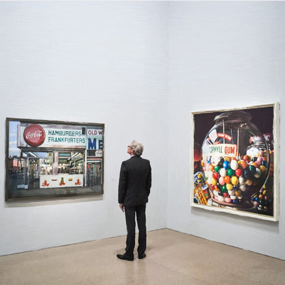 Das fotorealistische Digitalgemälde "Berlin" aus der Serie "Rueckenfiguren" von nostrokes zeigt einen Mann in einem schwarzen Anzug, der von hinten in einer Kunstgalerie steht. Er betrachtet zwei große, farbige Gemälde im Stil des Fotorealismus an einer weißen Wand. Das quadratische Werk ist in einer limitierten Edition auf Leinwand gedruckt und in der Online-Galerie ARTSPACER erhältlich.