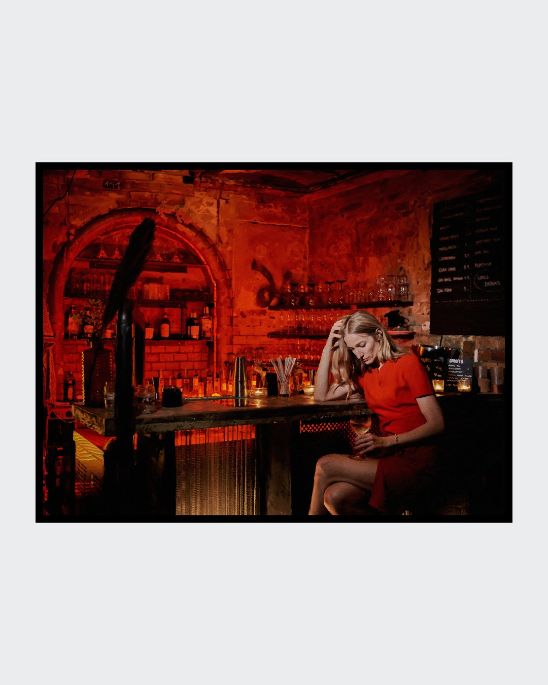 Das fotorealistische Digitalgemälde "Chablis bei Schlamassel" von nostrokesbitte zeigt eine blonde Frau im roten Kleid, die melancholisch an einer rot beleuchteten Bar sitzt und ein Glas Wein hält. Das Werk ist in limitierter Auflage bei ARTSPACER erhältlich.