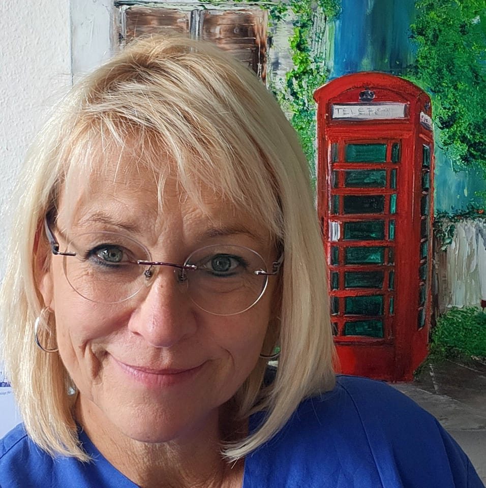 Person mit blondem Haar steht vor einem farbenfrohen Gemälde mit roter Telefonzelle und grüner Hausfassade im Hintergrund.