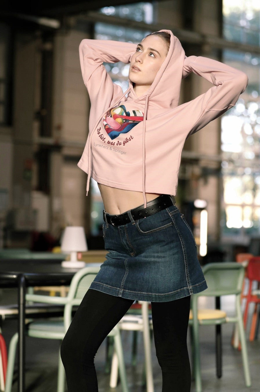 Ein kurz geschnittener, rosafarbener Hoodie mit überschnittenen Schultern. Extralange Bündchen mit Daumenloch und eine bedruckte Kunstgrafik auf der Vorderseite. Mode von Soulfashion .