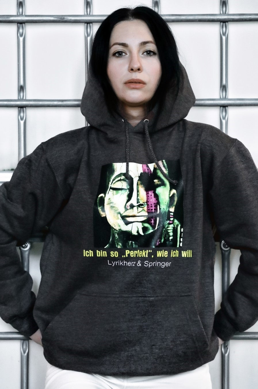 Ein anthrazitfarbener Unisex-Hoodie mit Kängurutasche und Kapuze. Auf der Vorderseite ist ein Kunstwerk gedruckt: Es zeigt ein abstrakt gestaltetes Gesicht, das halb modern, halb klassisch wirkt. 