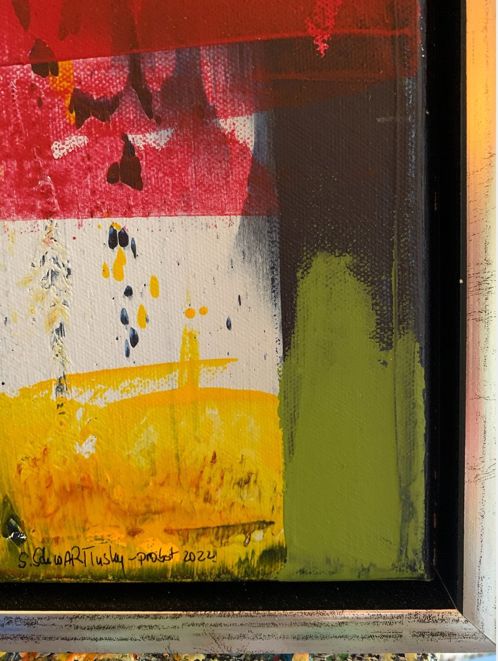 Abstraktes Acrylgemälde „Abstract World 5“ mit intensiven Rot-, Gelb-, Grün- und Dunkelblautönen, strukturreich geschichtet im silbernen Schattenfugenrahmen.